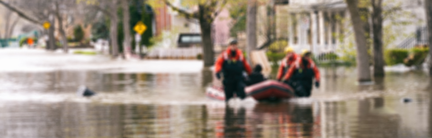 A rescue team in waders pulls a boat through flood waters.