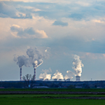 A row of power station chimneys emit plumes of steam into the air