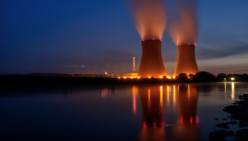 Large nuclear silos sit along a river and beneath a dark night