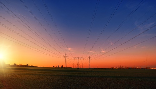 A picture of a pylon amongst the countryside during a sunset