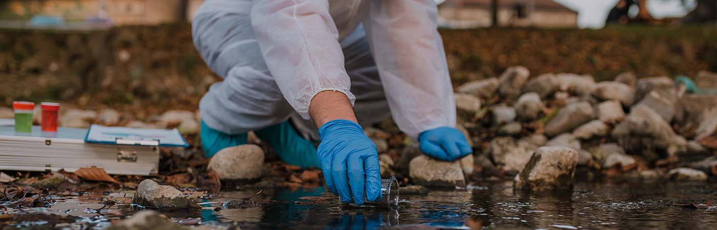 scientist collecting water sample from a stream