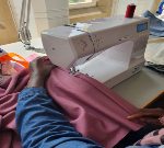 Person using a sewing machine and pink fabric