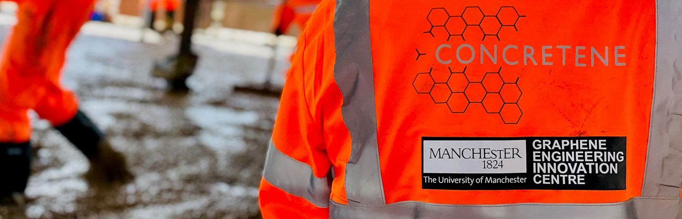 A man in a high-vis stands with his back to the camera as other workers pour a floor of 