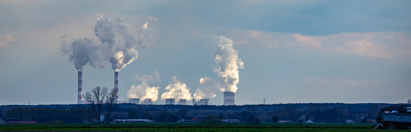 A row of power station chimneys on the horizon puff out steam into the sky.