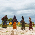 Women in traditional clothing collecting water